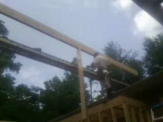Carpenter setting a ridge beam over a new addition frame — Ice Dam Removal by Roofing Brothers in Pittsfield