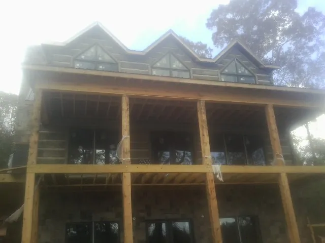 Dormers and porch framing on a large log home under construction — Roof Coating work by our crew in Pittsfield