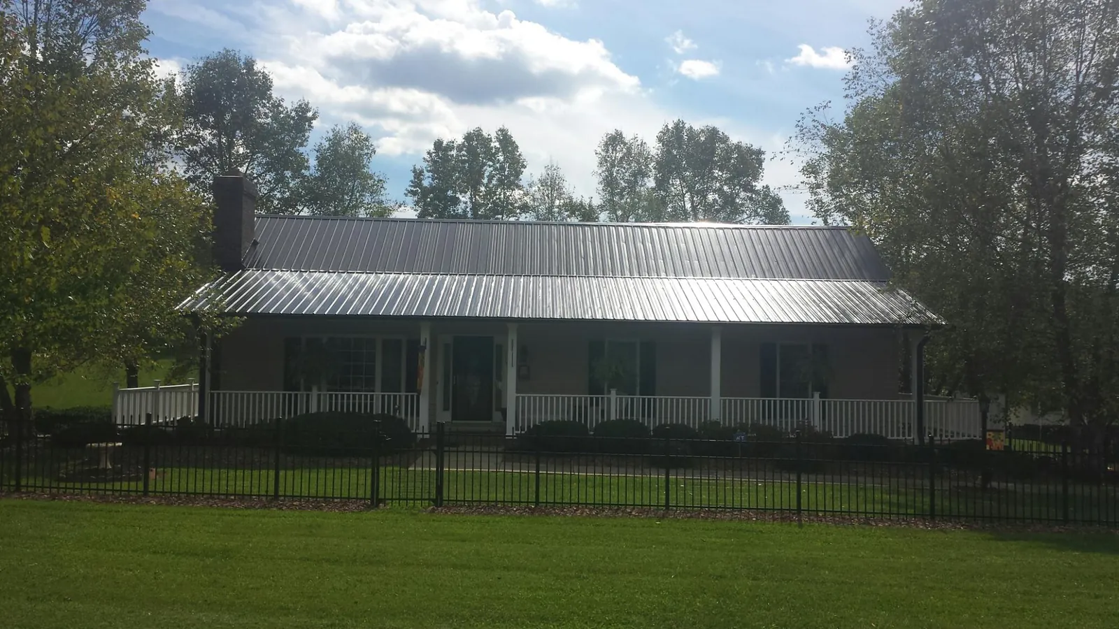 Gray metal roof on a brick ranch with a full width front porch — Gutter Guard Installation work by our crew in Pittsfield
